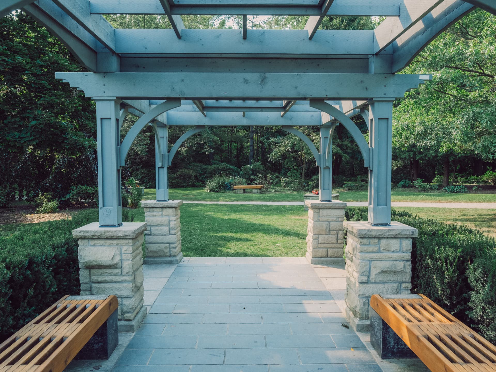 A photograph taken of a set of benches and a blue-green structure at the humber arboretum